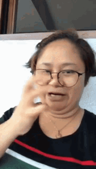 a woman wearing glasses and a necklace is making a funny face