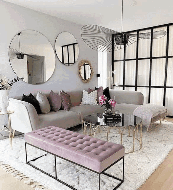 a living room with a white sectional couch and pink ottoman