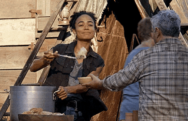 a woman in a plaid shirt is serving food to a man in a bowl