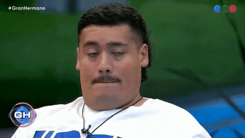 a man with a mustache is wearing a white shirt with the letters gh on the front