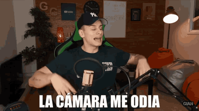a man stands in front of a microphone with the words la camara me odia on the bottom