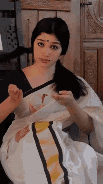 a woman in a white saree with a yellow stripe on the waist