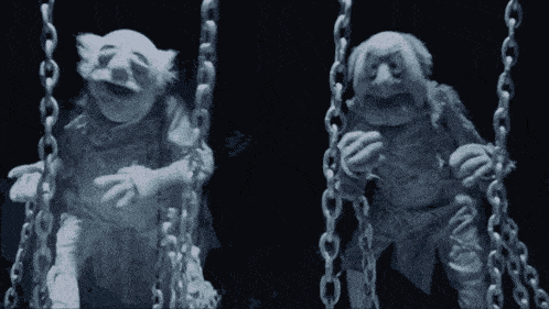 two ghosts are sitting on chains in the dark