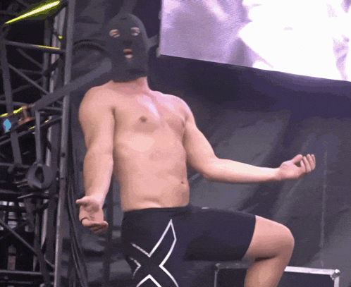 a shirtless man wearing a mask and shorts with the letter x on the side