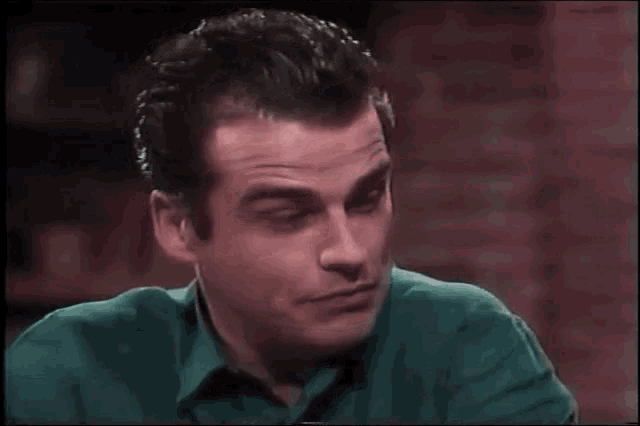 a man in a green shirt is smiling and looking at the camera