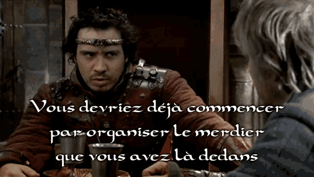 a man with a crown on his head is talking to another man with the words vous devriez deja commencer
