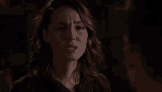 a close up of a woman 's face in a dark room with a serious look on her face .