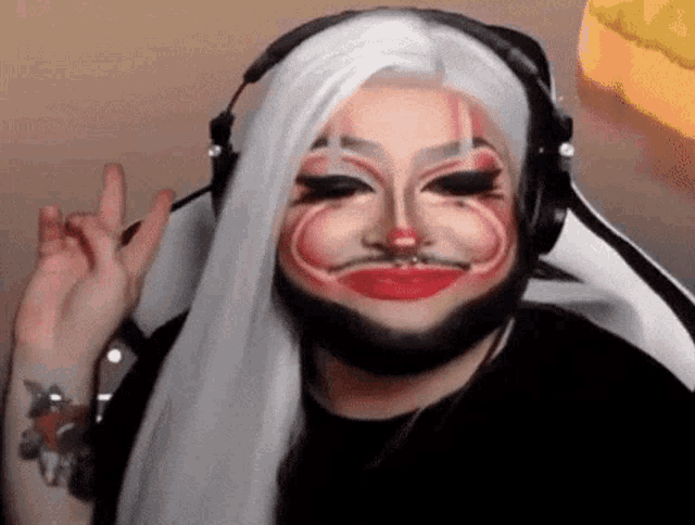 a drag queen with a beard and makeup on her face is wearing headphones .