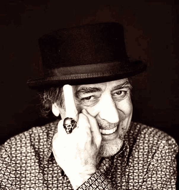 a man wearing a top hat and a skull ring is smiling