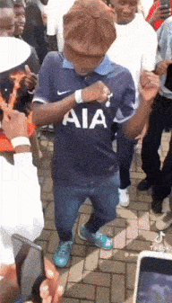 a man wearing a blue aia shirt is dancing in a crowd