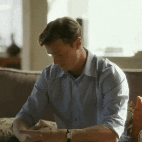 a man sits on a couch looking at his phone