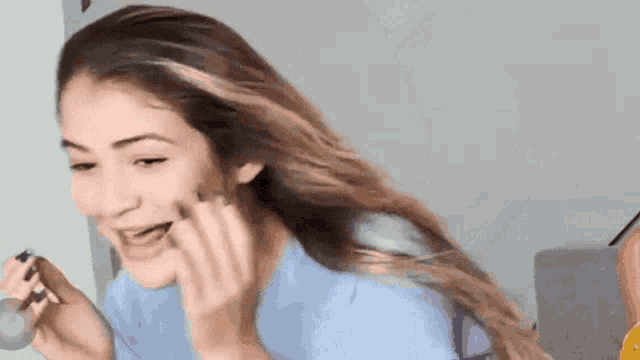 a woman in a blue shirt is applying makeup