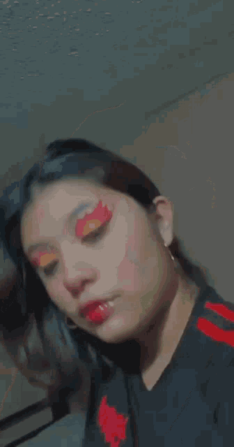 a close up of a woman 's face with red and yellow eyeshadow .