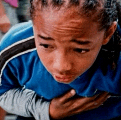 a young boy in a blue shirt has his hands on his chest