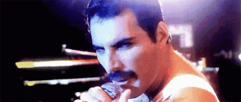 a man with a mustache is singing into a microphone on a stage .