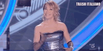 a woman in a strapless dress is smiling on a stage with the words trash italiano written above her