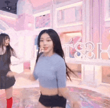a woman in a blue crop top and black shorts is dancing in a room .