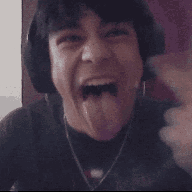 a man wearing headphones and a cross necklace makes a funny face