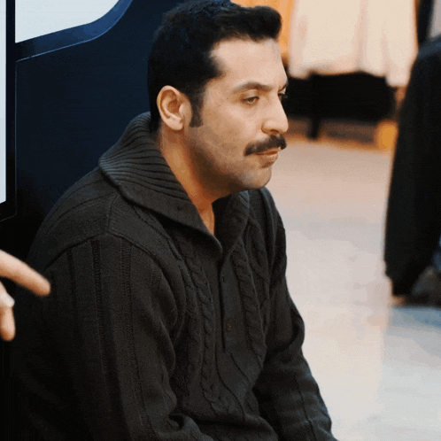a man with a mustache and a black sweater