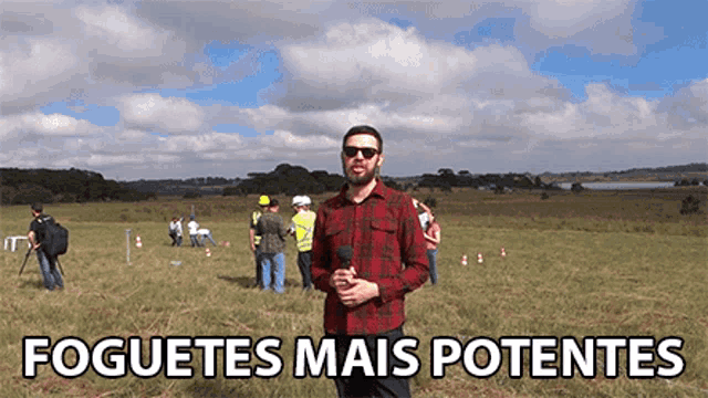 a man holding a microphone in a field with the words foguetes mais potentes written below him