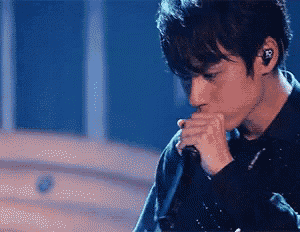 a man singing into a microphone with a r on his ear