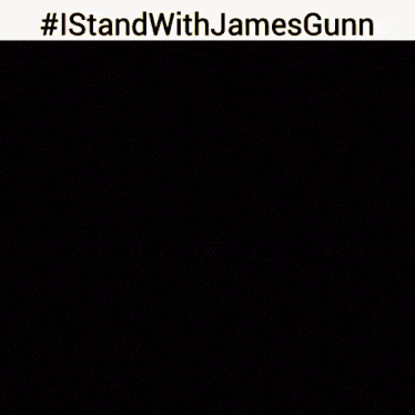 a man in a suit is standing in front of a fire with #istandwithjamesgunn