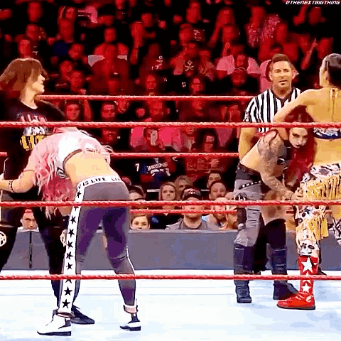 a group of women are wrestling in a ring with a referee watching .
