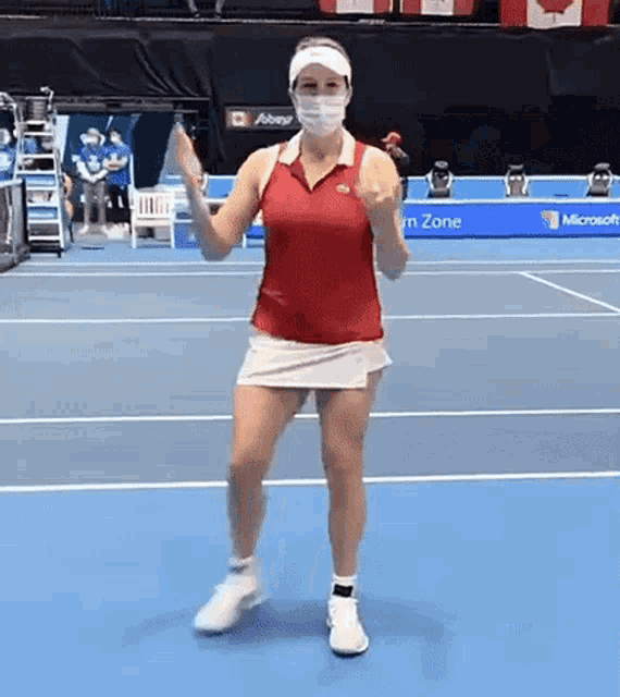 a tennis player wearing a mask is dancing on the court .
