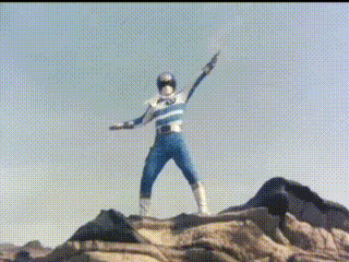 a man in a blue and white superhero costume is standing on top of a rocky hill .
