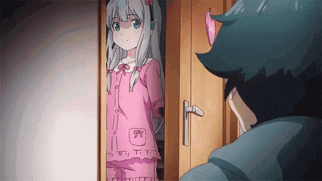 a boy and a girl are standing in a doorway . the girl is wearing a pink pajama set .