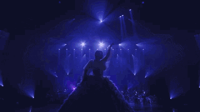 a woman in a long dress is standing in front of a crowd of people