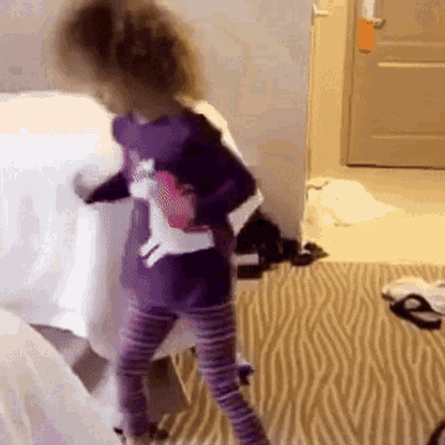 a little girl in a purple shirt with a white cat on it