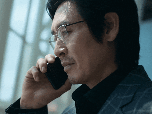 a man wearing glasses is talking on his cell phone