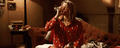 a woman is drinking from a bottle while sitting on a couch in a living room .