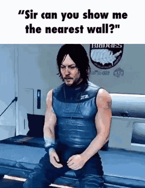 a man in a leather vest is sitting on a couch in a room and talking to someone .