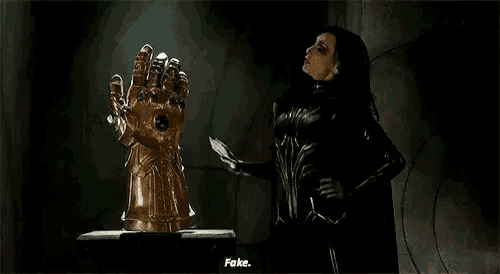 a woman in a black suit is holding a hammer and a glove .