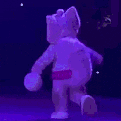 a purple teddy bear is dancing in the dark
