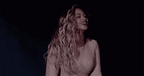 a woman with long curly hair is dancing in the dark .