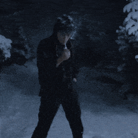 a man in a black jacket is standing in the snow holding a flashlight