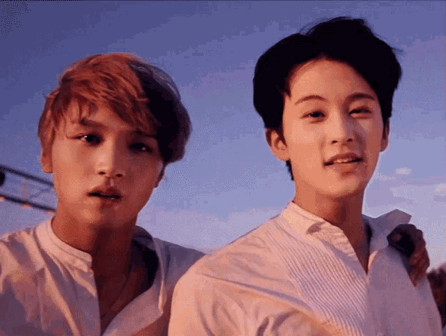 a couple of young men standing next to each other with a blue sky in the background