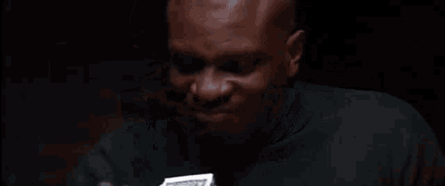 a bald man is holding a stack of money in front of his face .