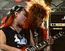 a woman with red hair is playing a guitar next to a marshall amplifier