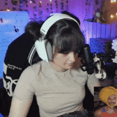 a woman wearing headphones stands in front of a microphone in a room
