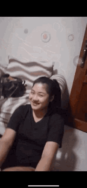a woman in a black shirt is smiling while sitting on a couch .