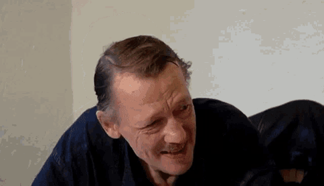 a man with a mustache is making a funny face while sitting in a chair .