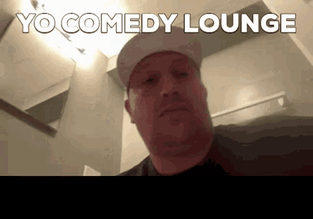 a man wearing a hat is looking at the camera with the words yo comedy lounge above him .