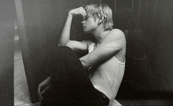 a black and white photo of a man in a tank top sitting down
