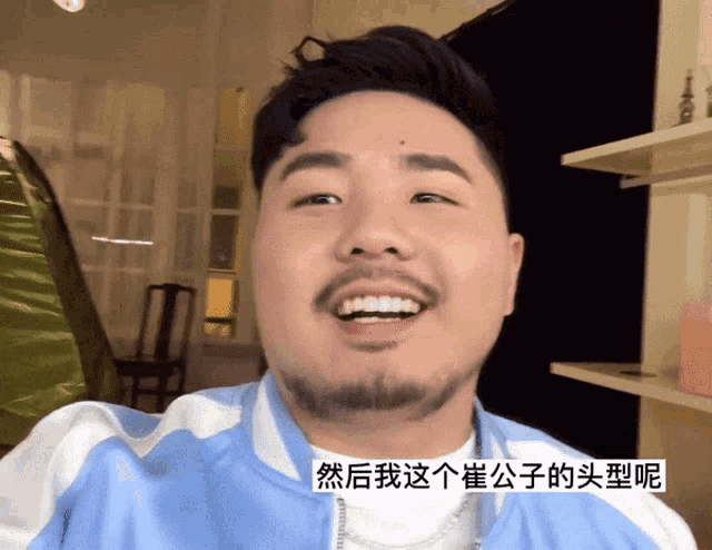 a man with a beard is smiling in a room with chinese writing on the bottom