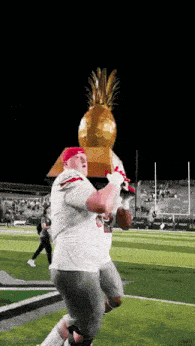 a football player is holding a pineapple trophy