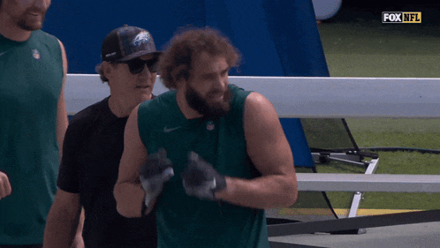 a man wearing a eagles hat stands next to a man wearing a black shirt